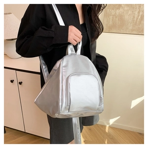 Silver teardrop backpack with sleek metallic finish shown on model in home setting