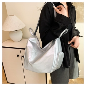 Detail view of large silver metallic hobo bag showing side zipper pocket on shoulder