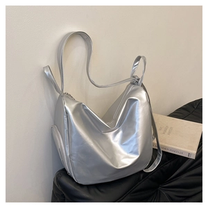 Detail of silver metallic tote bag featuring wide shoulder straps and side zipper pocket
