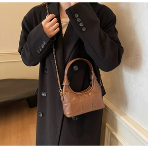 Détail d'un sac à main en cuir matelassé marron avec bandoulière chaîne dorée élégante
