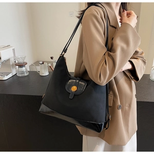 Détail d'un sac cabas noir en cuir avec boucle en métal doré et fine bandoulière élégante