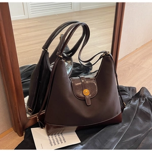 Détail du sac hobo vintage marron foncé avec emblème doré et texture cuir brillant