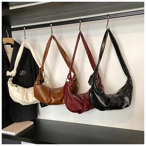 Detailed row of pleated crescent bags in beige, brown, burgundy, and black soft leather