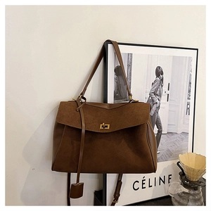 Close-up of brown suede tote bag featuring a gold twist lock and elegant leather charm
