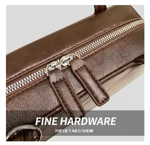 Close-up of premium dark brown lychee leather texture with dual silver metal zippers