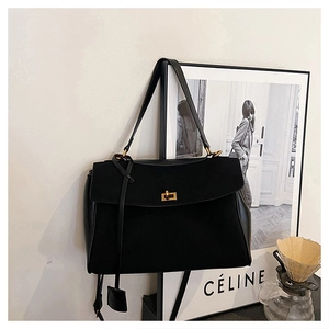 Detail of a black faux suede tote bag with a gold square twist lock and leather tag