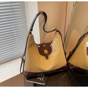 Détail d'un grand sac à bandoulière bicolore en tissu beige et bordure marron foncé