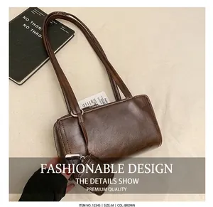 Detail of a minimalist dark brown leather bowling bag with side pouch on a gray coat