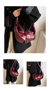 Close-up of pleated wine red crescent bag with glossy oil-wax leather and knot detail
