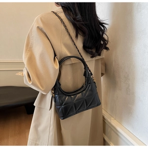 Détail du sac matelassé noir avec chaîne dorée et poignée supérieure arrondie