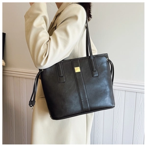 Detail showing high-quality black PU leather tote bag with gold metal buckle and side drawstrings