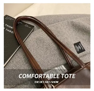 Close-up of thick double handles on a vintage brown leather bowling bag with fine stitching
