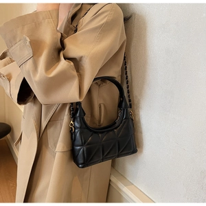 Sac en cuir noir matelassé avec bandoulière chaîne élégante porté par un mannequin urbain