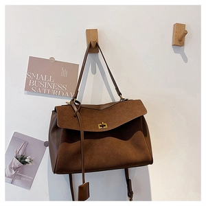 Detail of brown suede tote bag with golden metal twist lock and smooth leather patchwork