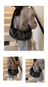 Detail of black glossy croissant bag with ruched texture and wide shoulder strap