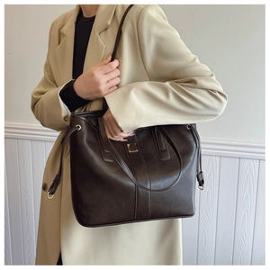 Detail of a large coffee brown tote bag with premium matte leather and metal accent