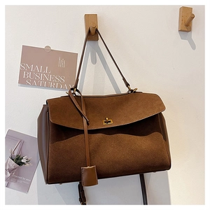 Detail of vintage brown suede tote bag with golden lock and leather patchwork