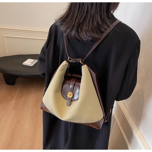 Détail du sac à dos en tissu beige et cuir marron porté avec boucle dorée
