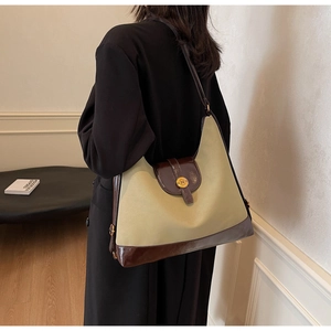 Détail du sac hobo en toile olive, garniture en cuir marron et boucle dorée avec un N