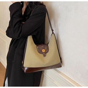 Détail du sac bicolore kaki et marron avec une boucle métallique vintage ronde