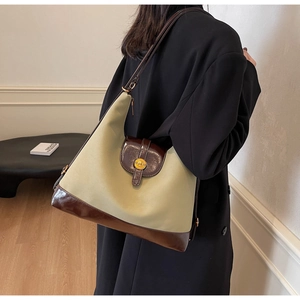 Détail du sac cabas en toile beige avec bordures en cuir brun et boucle en métal