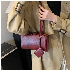 Close-up of deep red glossy leather shoulder bag with matching mini charm pendant