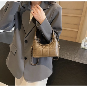 Détail d'un sac à bandoulière matelassé marron avec chaîne vintage et poignée en cuir