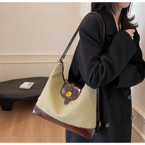 Détail du sac cabas en toile et cuir contrasté avec boucle dorée à l'épaule