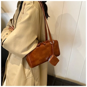 Detailed side view of vintage brown leather shoulder bag with mini pouch accessory