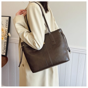 Detailed view of the dark brown leather tote bag with stylish side drawstring and gold metal