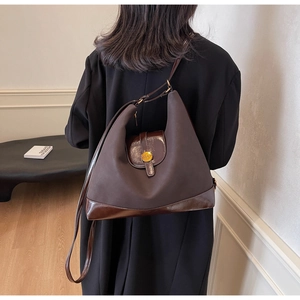 Détail du sac à bandoulière en daim marron avec boucle logo N dorée et finitions cuir