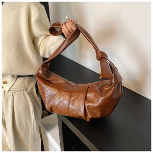 Detail of a brown pleated crescent bag with a knotted strap and soft leather texture