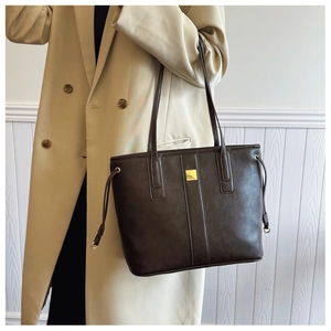 Brown leather tote bag featuring elegant gold square hardware and slim double handles