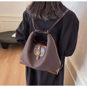 Détail d'un sac à dos en cuir et tissu marron foncé avec boucle magnétique dorée
