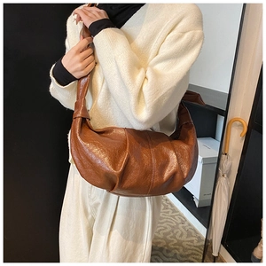 Detailed view of brown ruched crescent bag with soft textured faux leather finish