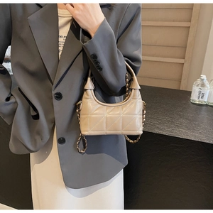 Détail du sac à main matelassé beige avec bandoulière chaîne porté sur un blazer gris