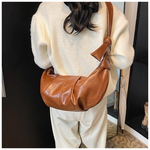 Detailed view of brown soft leather crescent bag with stylish knot strap and pleated texture