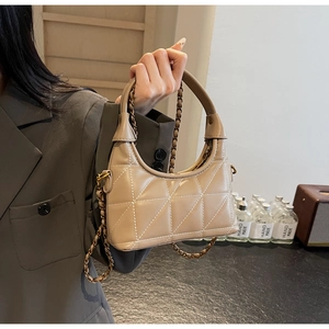 Détail du sac à bandoulière matelassé beige avec surpiqûres blanches et chaîne dorée