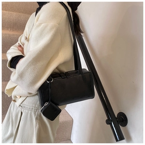 Close-up of black minimalist bowling bag with a small square coin purse on the shoulder strap