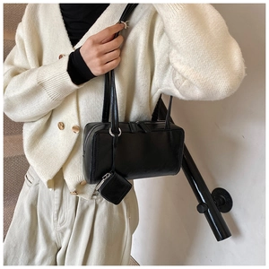 Model view of black bowling underarm bag with a mini square coin purse attachment