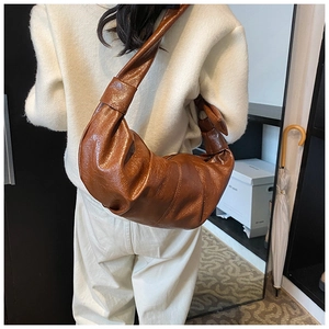 Detail view of the soft wrinkled texture and dark brown leather on the hobo bag