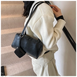 Detail of black matte leather shoulder bag with zipper and mini coin purse charm