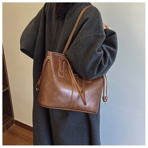 Detail view of a vintage dark brown tote bag showing matte texture and side drawstring