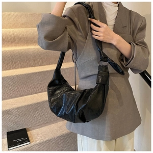 Detail of black glossy pleated shoulder bag featuring soft texture and wide strap