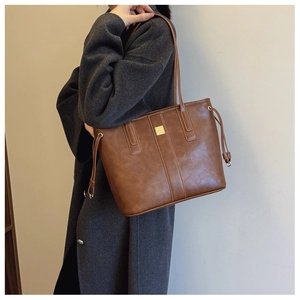 Close-up of caramel tote bag with drawstring detail and square metal buckle decoration