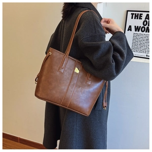 Detailed view of brown PU leather tote bag with square buckle and decorative side straps