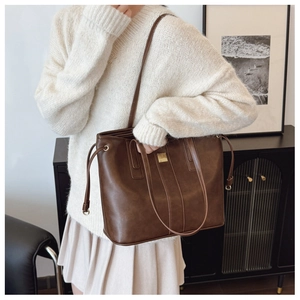 Close-up of a brown oversized tote bag with metal hardware and adjustable shoulder strap