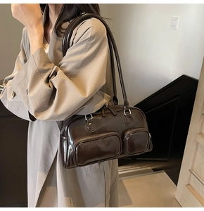 Detail of a dark coffee patent leather bowling bag styled with a classic beige trench coat
