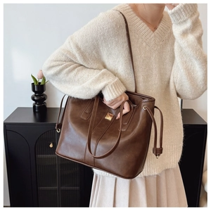 Detail of deep brown large tote bag featuring gold buckle and textured leather finish