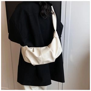 Detailed back view of a soft pleated croissant bag in creamy white on a model's shoulder